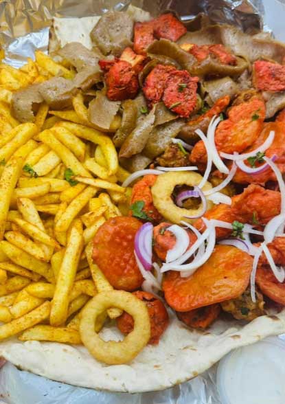 Sizzling doner kebab with chips and sauce served at Village Takeaway in Glenboig